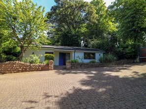 A single-story house with a paved driveway, a blue door, and a brick wall. - Elmcroft (Nottingham)