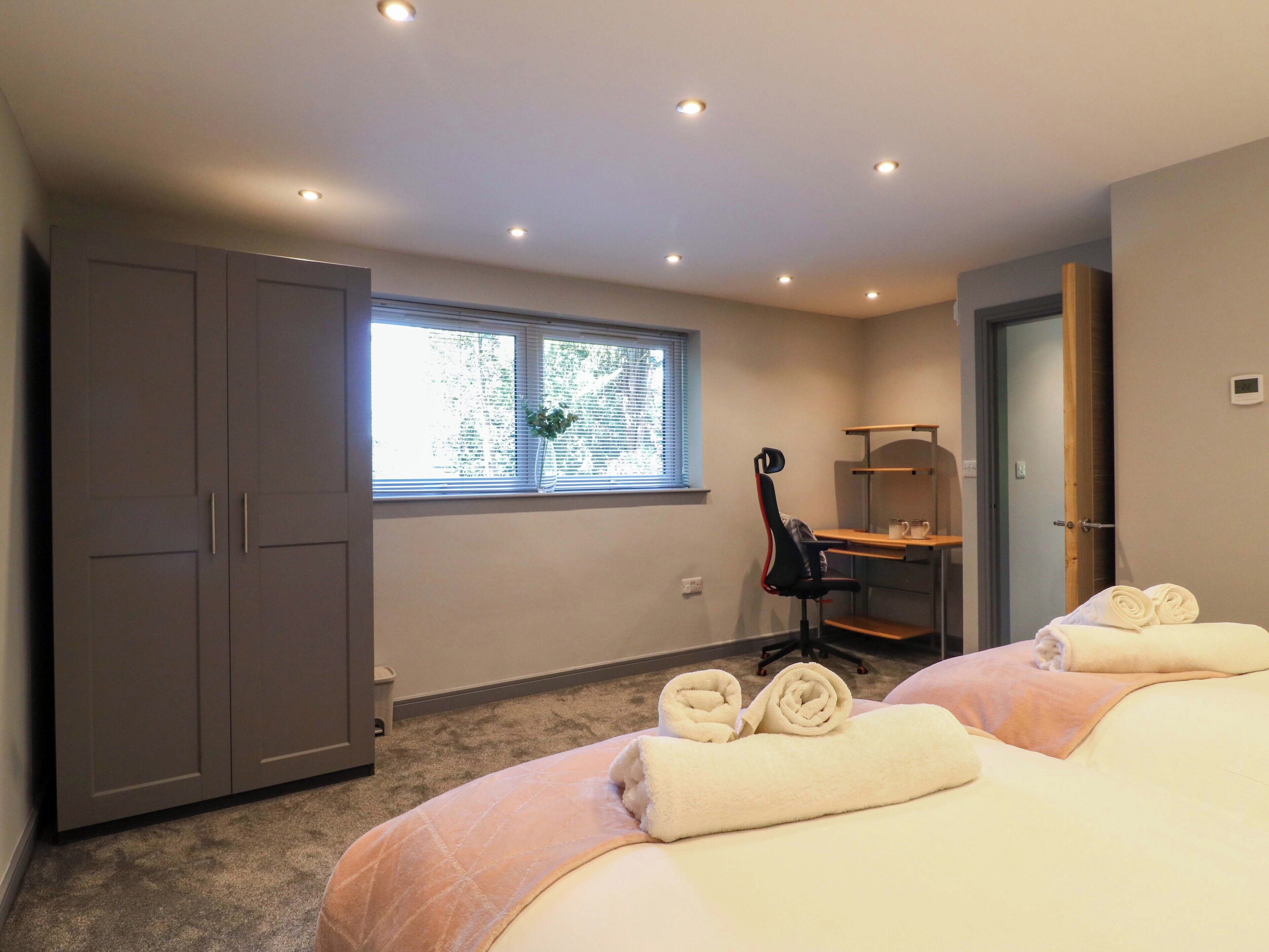 A bedroom with a bed, a desk, a chair, and a wardrobe.