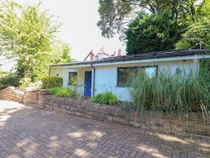 A single-story house with a blue door, a brick wall, and a paved driveway.