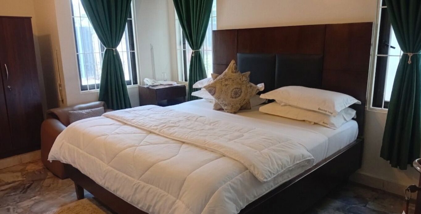 A bed with a white quilt, a decorative pillow, and a bedside table with a lamp.