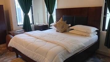 A bed with a white quilt, a decorative pillow, and a bedside table with a lamp.
