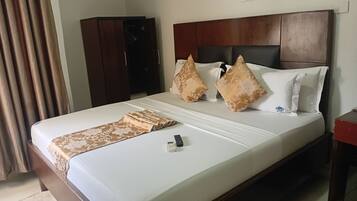 Habitación de hotel con cama, cabecera de madera, manta marrón estampada y control remoto sobre la cama.