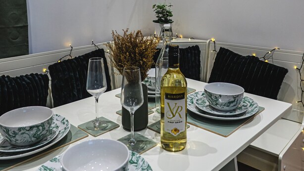 Een eettafel is gedekt met borden, glazen en een fles, omringd door zwarte fauteuils.