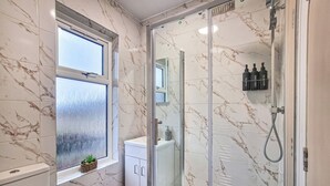 Een moderne badkamer met een douchecabine van glas, een toilet en een wastafel.