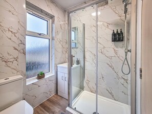 A modern bathroom with a glass-enclosed shower, a toilet, and a sink. - Shrubberies Suite (Derby)