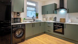 Een moderne keuken met een wasmachine, magnetron, broodrooster en oven.