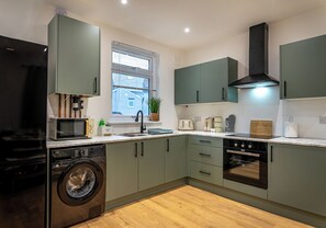 Eine moderne Küche mit Waschmaschine, Mikrowelle, Toaster und Backofen.