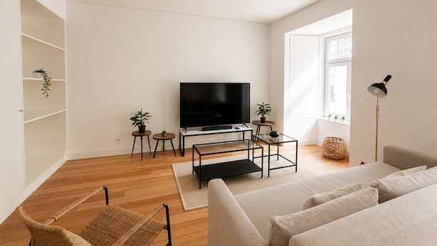 A modern living room with a flat-screen TV, a sofa, a wicker chair, and a floor lamp. - Elegant 1 Bed Apartment in Lisbon (Lisboa)