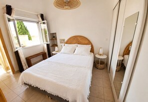 A bedroom with a large bed, a bedside table, a mirror, and a window with curtains. - A retreat for two, nestled between the sea and the Thau. Air conditioning, Wi-Fi, private parking, patio. (Marseillan)