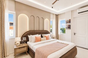 A modern bedroom with a large bed, bedside tables, a ceiling fan, and a view of the outside.