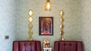 A room with two leather armchairs, a small white table with a vase and wine glasses, and a hanging light fixture.