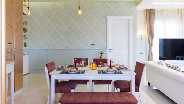 A dining area with a table set for four, a sofa, and a television in the background.