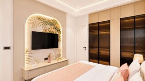 A modern bedroom with a large bed, a TV mounted on a wall with a decorative arch, a bedside table with a lamp, and a wardrobe with a mirrored door.