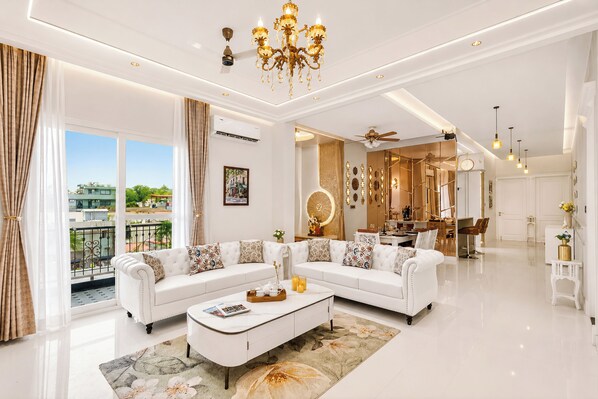 A modern living room with a sectional sofa, a coffee table, and a chandelier.