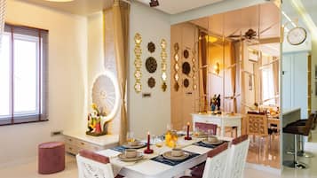 Comedor con mesa preparada para cuatro personas, ventilador de techo y barra con taburetes.