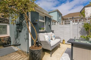 Un espace patio aménagé avec un canapé en osier, une plante en pot et une petite table.