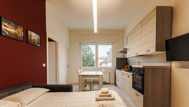 A bedroom with a bed, a bedside table, a window, and a view of the outside. - Tosa Apt - 500m from the Racetrack - Free WiFi & Parking (Imola)