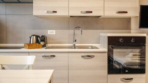 A modern kitchen with light wood cabinets, a stainless steel sink, and a built-in oven. - Tosa Apt - 500m from the Racetrack - Free WiFi & Parking (Imola)