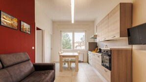 A modern apartment with a living room, dining area, kitchen, and a large window. - Tosa Apt - 500m from the Racetrack - Free WiFi & Parking (Imola)