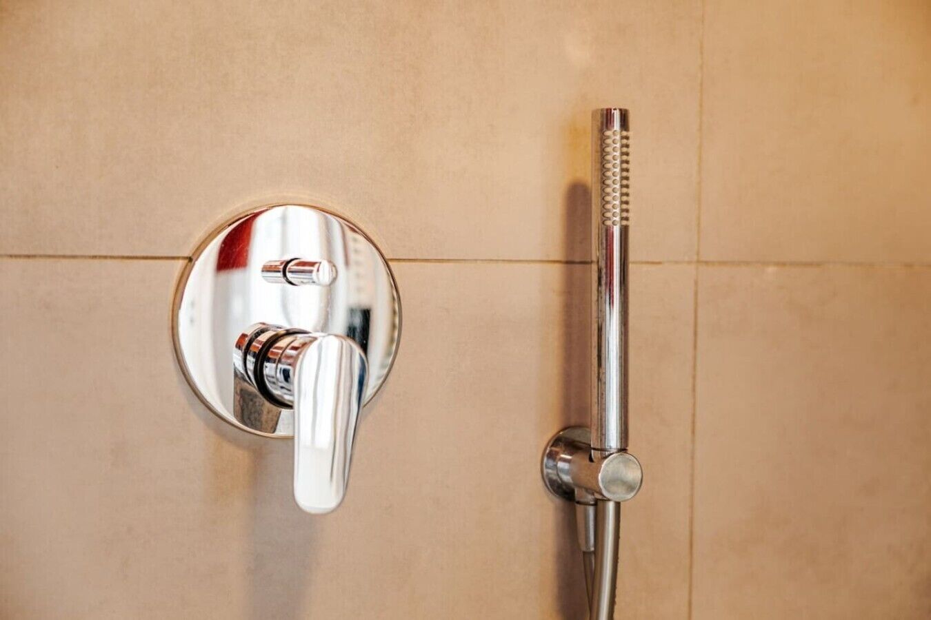 Un baño con cabezal de ducha cromado y grifo empotrado en la pared.