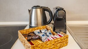 A kitchen area with a woven basket containing various packaged food items, a stainless steel kettle, and a coffee machine. - Tosa Apt - 500m from the Racetrack - Free WiFi & Parking (Imola)