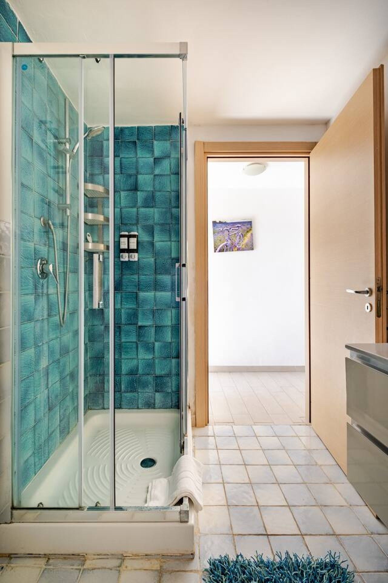 Une salle de bain moderne avec une douche à parois de verre, un sol carrelé et une porte en bois.