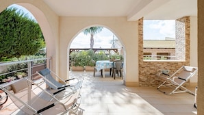 A covered outdoor area with lounge chairs, a table, and potted plants. - Sicilian Oasis, 200 meters from the Sea (Ognina)