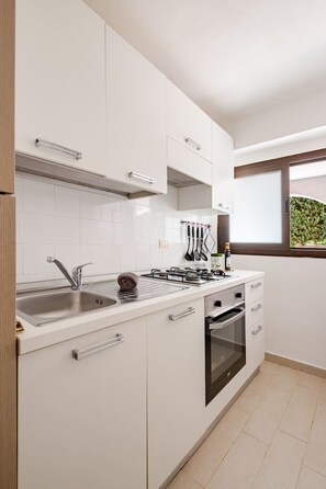 A modern kitchen with white cabinets, stainless steel appliances, and a window with a view of greenery. - Sicilian Oasis, 200 meters from the Sea (Ognina)