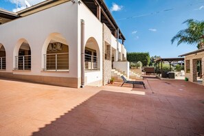 Un bâtiment doté d’un patio couvert, d’un espace extérieur aménagé pour s’asseoir et d’un escalier menant à un niveau supérieur.