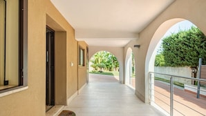 A covered corridor with a tiled floor, arched openings, and a metal railing on one side. - Sicilian Oasis, 200 meters from the Sea (Ognina)