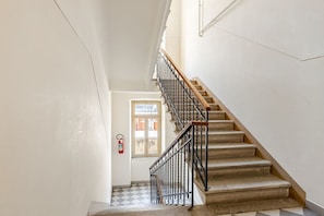 A staircase with a wooden handrail and black metal balusters, leading to a door with a window. - Comfort & Space with Parking Near the Center of Trieste (Trieste)