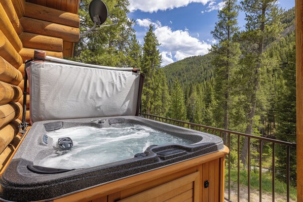 A hot tub on a balcony with a forest view.