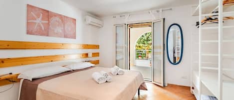 A hotel room with a bed, a wardrobe, and a view of the outdoors.