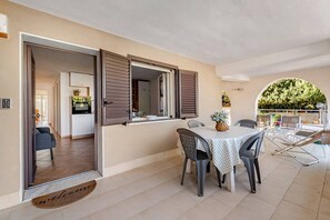 Ein Essbereich mit Tisch und Stühlen, eine durchgehende Tür zur Küche und ein Balkon mit Sitzgelegenheit im Freien.