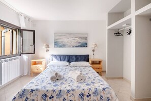 Ein Schlafzimmer mit einem Bett, zwei Nachttischen, einem Fenster, einem Bild und einem Kleiderschrank.