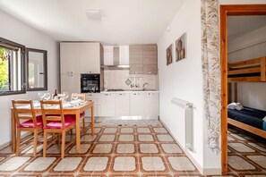 A compact kitchen with white cabinets, a dining table with chairs, and a radiator. - Relax in a Villa Near the Sea with a Private Terrace (Ognina)