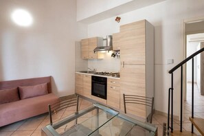 Una cucina compatta con piano cottura a gas, forno e arredamento moderno.