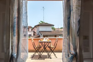 Un balcone con tavolo e sedie, una bottiglia e della frutta.