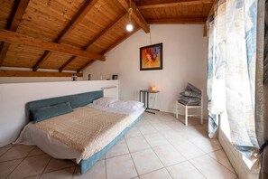 Una camera da letto con un letto, un comodino con una lampada, una sedia e un quadro appeso al muro.