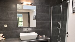 Een moderne badkamer met een grote spiegel, een wit wastafelmeubel en een douchecabine.