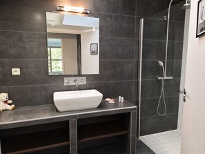 A modern bathroom with a large mirror, a white sink, and a shower area. - Villa Locquénolé overlooking Morlaix Bay (Locquénolé)