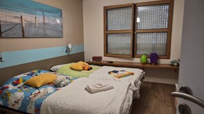 A bedroom with two beds, a window with blinds, a wall-mounted lamp, and a painting. - Villa Locquénolé overlooking Morlaix Bay (Locquénolé)