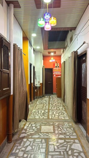 A corridor with patterned flooring, a series of doors on both sides, and hanging lights.