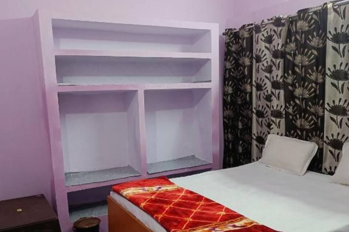 Ein Schlafzimmer mit einem Bett, einem Kleiderschrank, einem kleinen Tisch und einem Mülleimer.