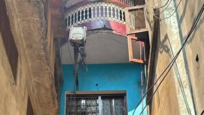 A narrow alley with a blue building featuring a sign for a guest house.