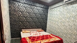 A bedroom with a bed, a ceiling fan, and patterned walls.