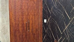 A room with a wardrobe, a chair, and a patterned wall.