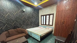 A bedroom with a bed, a sofa, a chair, and a small table.