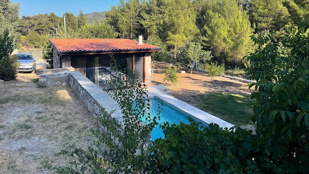Una casa con piscina, rodeada de árboles y un coche aparcado cerca.