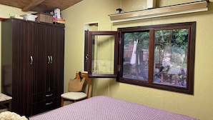 Un dormitorio con cama, armario, silla y ventana con vistas a muebles de exterior.